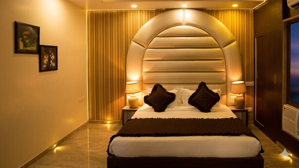 A hotel room with a large bed, a curved ceiling design, and a television on the right side. - Hotel The Grand Majestic (Jaipur)