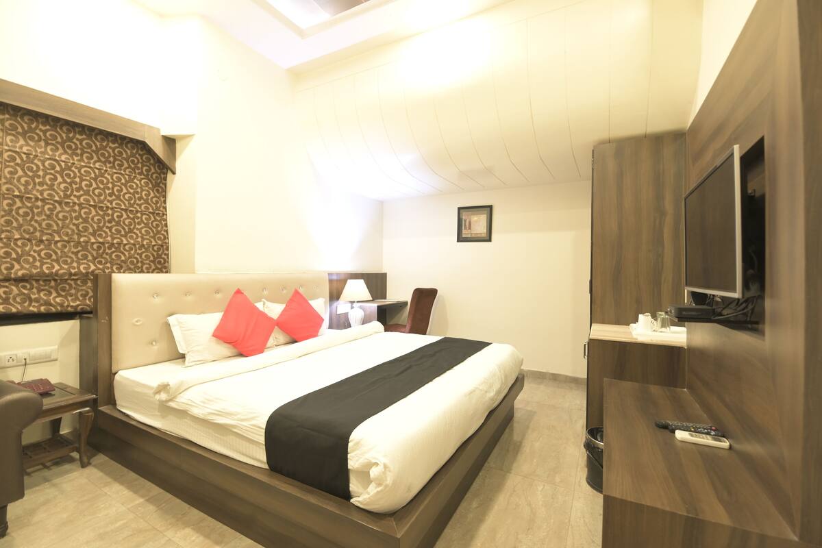 Una habitación de hotel con cama, escritorio, silla, televisor y baño.