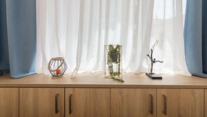 A wooden cabinet with a candle holder, a potted plant, and a sculpture on top. - Athens Syntagma Ermou (Athens)