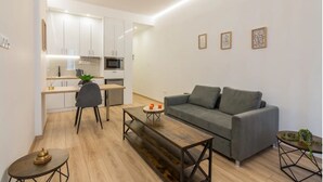 A modern apartment with a kitchen, a grey sofa, a wooden coffee table, and a small round table with a plant. - Athens Syntagma Ermou (Athens)