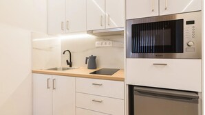A modern kitchen with white cabinets, a stainless steel microwave, and a built-in dishwasher. - Athens Syntagma Ermou (Athens)