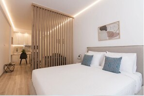 A modern hotel room with a large bed, a desk, and a sliding partition.
