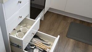 Eine Küche mit einer Schublade, die Tassen, Besteck und einem Pyrex-Behälter enthält.