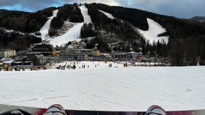 A ski resort with a chairlift, snow-covered slopes, and buildings in the background.