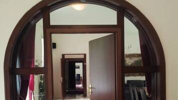 Un arco de entrada conduce a un pasillo con suelo de baldosas y una vista de una habitación con cama y ventana.