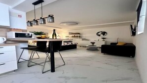 Una cocina moderna con comedor, un sofá negro, una mesita redonda y un globo en la pared.
