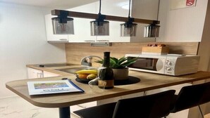 Una cocina moderna con encimera de madera, microondas, planta y botella de vino.