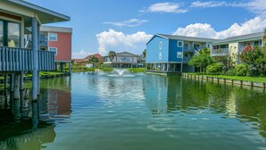 A waterfront hotel with a central fountain, multiple balconies, and a clear view of the water.