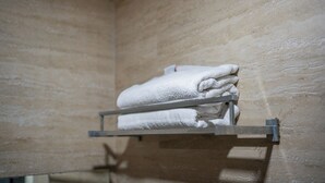 Ein Badezimmer mit Handtuchhalter, der gefaltete Handtücher an einer strukturierten Wand zeigt.