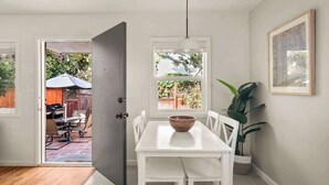 A dining area with a white table, chairs, a bowl, a hanging light, and a potted plant. - PB Bungalow-Private fenced yard-Parking-Remodeled! (San Diego)