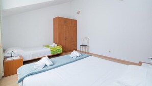 Ein Schlafzimmer mit zwei Betten, einem Holzschrank, einem Sessel und einem Nachttisch mit Lampe.