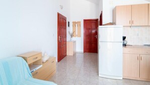 Eine kleine Küche mit Holzschränken, einem weißen Kühlschrank und einer Arbeitsplatte.