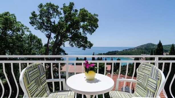 A balcony with two striped chairs and a small round table, overlooking a scenic view of the sea and hills. - Apartments Marmo - Superior One Bedroom Apartment with Balcony and Sea View (Apartman 3) (Mlini)