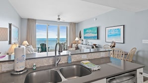 Una cocina moderna con una isla grande, pileta de acero inoxidable y vista al océano.