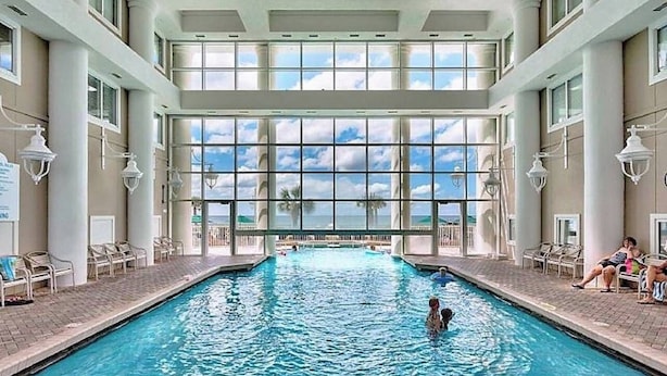 Una piscina interior con vistas despejadas al cielo y palmeras.