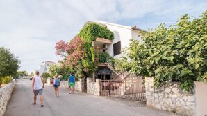 Una calle residencial con casas, un muro de piedra y una verja.