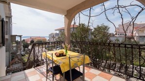 Ein Balkon mit einem gelben Tisch, Stühlen und einem Blumenstrauß.