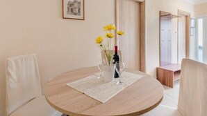 A round dining table with a vase of yellow flowers and wine glasses, surrounded by upholstered chairs. - Apartments Fidelis - Two Bedroom Apartment with Terrace and Pool View(5) (Okrug Gornji)