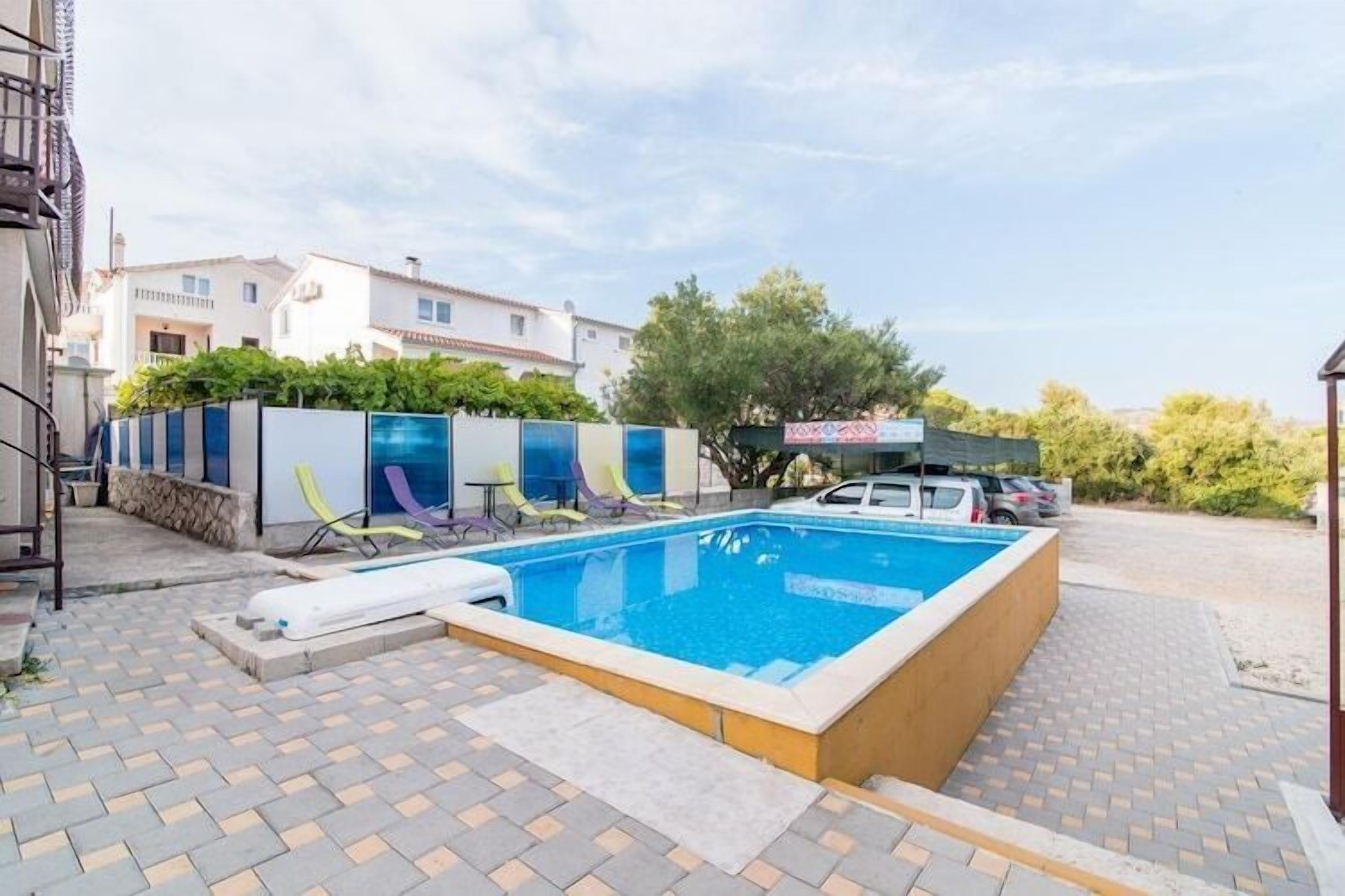 Et rektangulært pool med træterrasse, omgivet af en belagt patio.