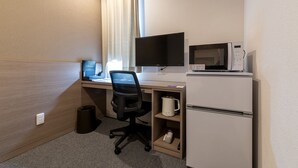 Habitación de hotel con escritorio, televisión de pantalla plana, microondas, cafetera y refrigerador pequeño.