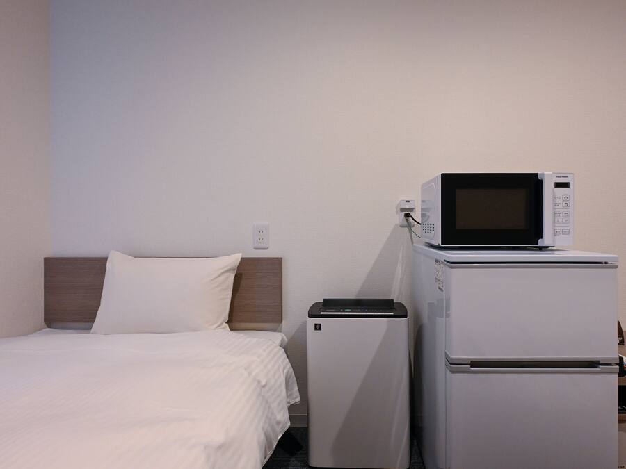 Ein Hotelzimmer mit einem Bett, einer Mikrowelle und einem Kühlschrank.