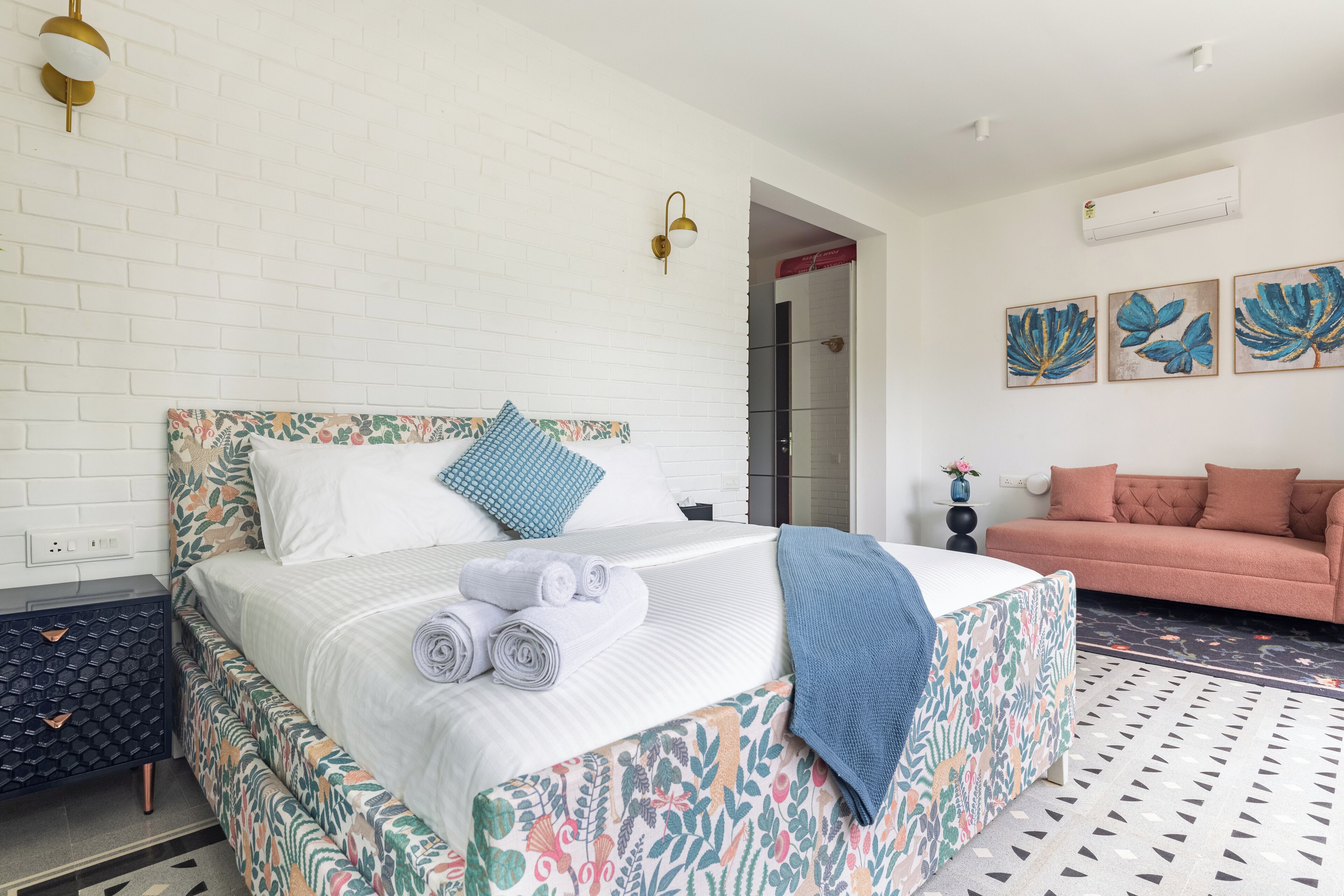 Quarto com cama, mesa de cabeceira, sofá e obras de arte nas paredes.
