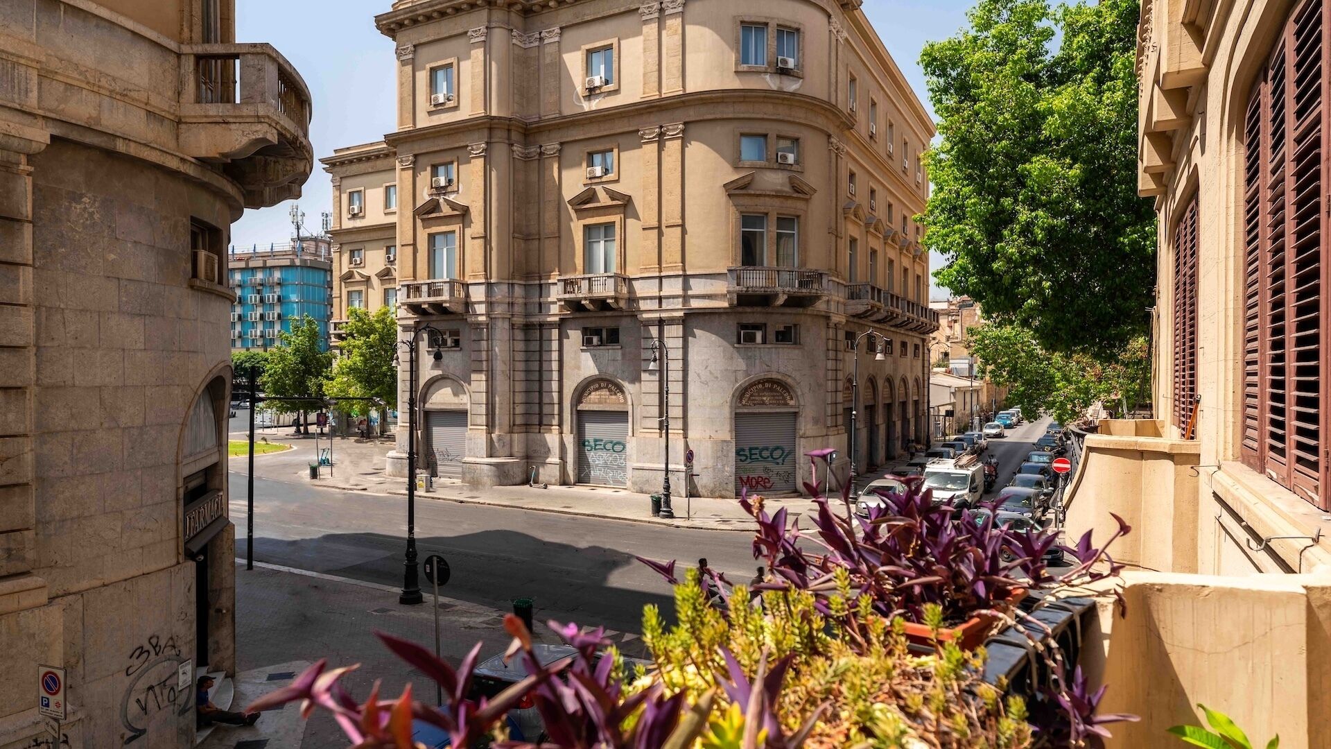 A street view with a building featuring arched windows and a balcony.