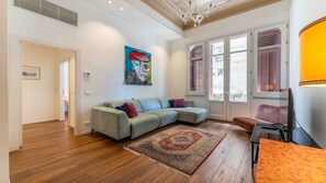 Una sala de estar moderna con un sofá seccional, un tapete estampado y un ventanal con contraventanas.