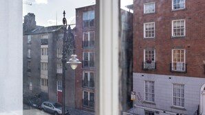 Una vista di una strada con edifici, tra cui un edificio in mattoni rossi con numerose finestre e balconi.