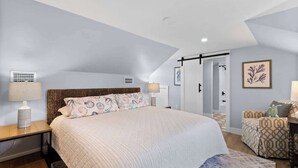 Une chambre avec un grand lit, une table de chevet, une lampe, une armoire et une chaise.