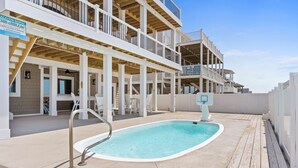 A multi-story building with a pool area, outdoor seating, and a sign indicating a vacation rental.