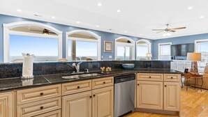A spacious kitchen with a large island, built-in appliances, and a view of the ocean.