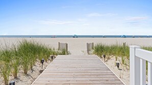 A wooden boardwalk leading to a beach with a clear sky.