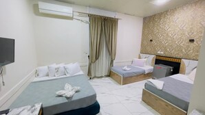 A hotel room with two beds, a flat-screen TV, an air conditioner, and a curtain. - One Season Hostel (Cairo)
