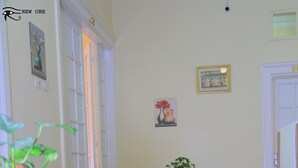 A hallway with a patterned carpet, a sofa with cushions, a potted plant, and a door with a number. - One Season Hostel (Cairo)