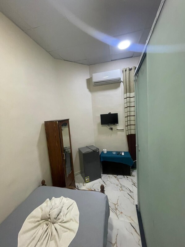 A bedroom with a bed, a wardrobe, a desk, an air conditioner, and a television. - One Season Hostel (Cairo)