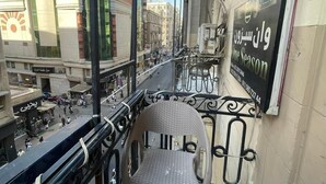 A balcony with a chair, a signboard, and a view of the cityscape. - One Season Hostel (Cairo)