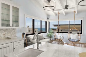 A modern kitchen with a large island, hanging chairs, and a view of the ocean. - Oceanview 2,200 SF Home | Steps to Beach | Gym (Manhattan Beach)