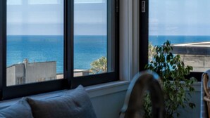 Una habitación con ventanas amplias que ofrecen vistas al mar y edificios.