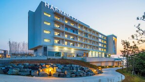 A modern hotel with multiple floors and balconies, featuring a well-lit facade and a landscaped entrance area. - HAENAM 126 HOTEL (Haenam)