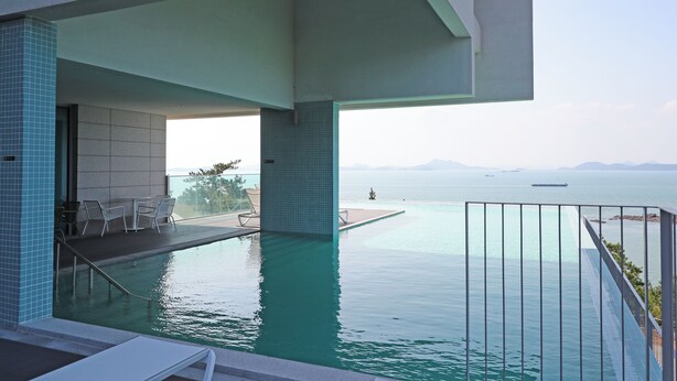 A pool area with a view of the sea, a covered seating area, and a railing. - HAENAM 126 HOTEL (Haenam)