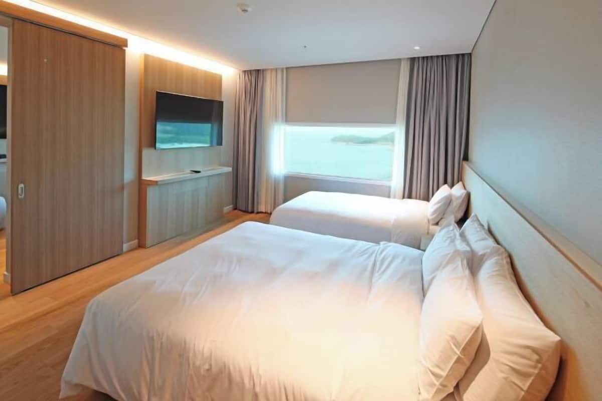 Ein Hotelzimmer mit Bett, Fernseher, Kleiderschrank und einem Fenster mit Vorhängen.