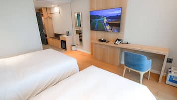 Een hotelkamer met twee bedden, een bureau met stoel, een televisie en een spiegel.