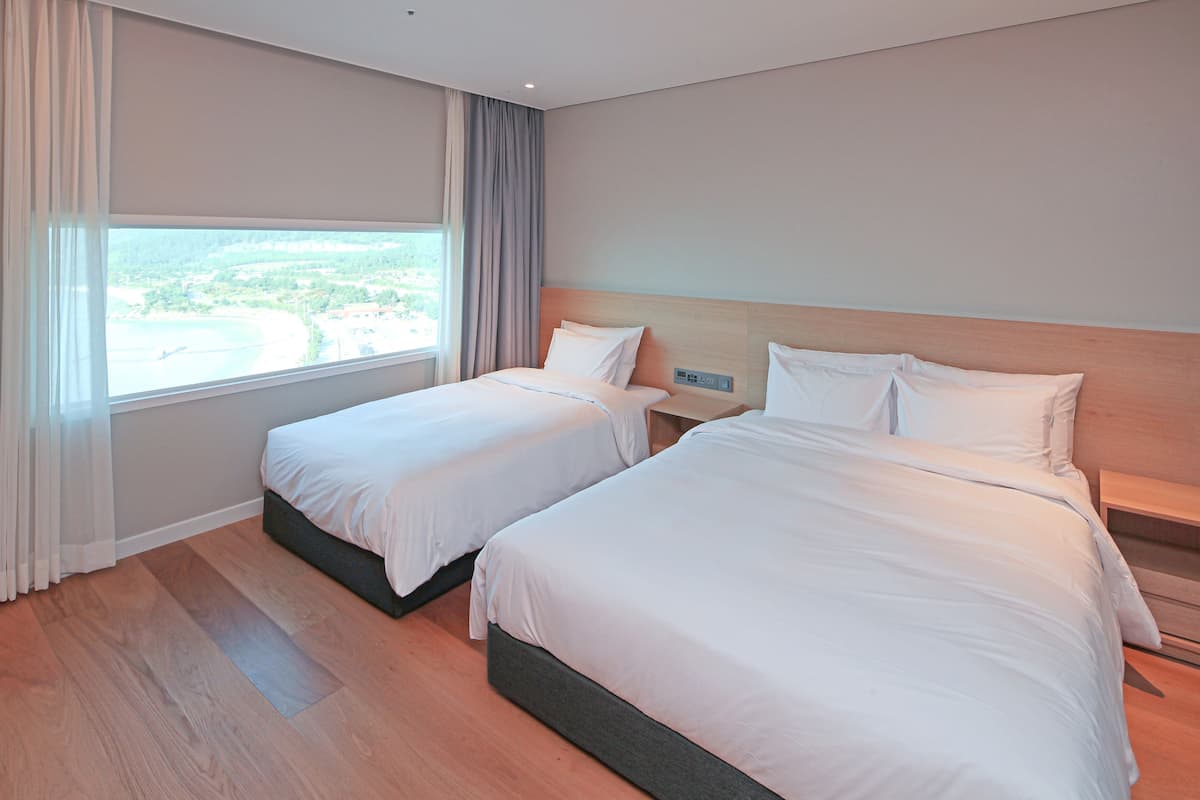 Ein Hotelzimmer mit zwei Betten, einem großen Fenster mit Blick und einem Holzboden.