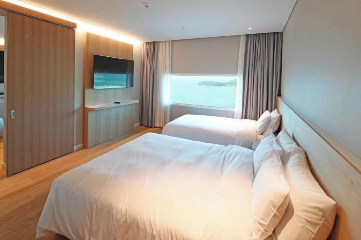 Habitación de hotel con cama, televisión, armario y ventana con cortinas.