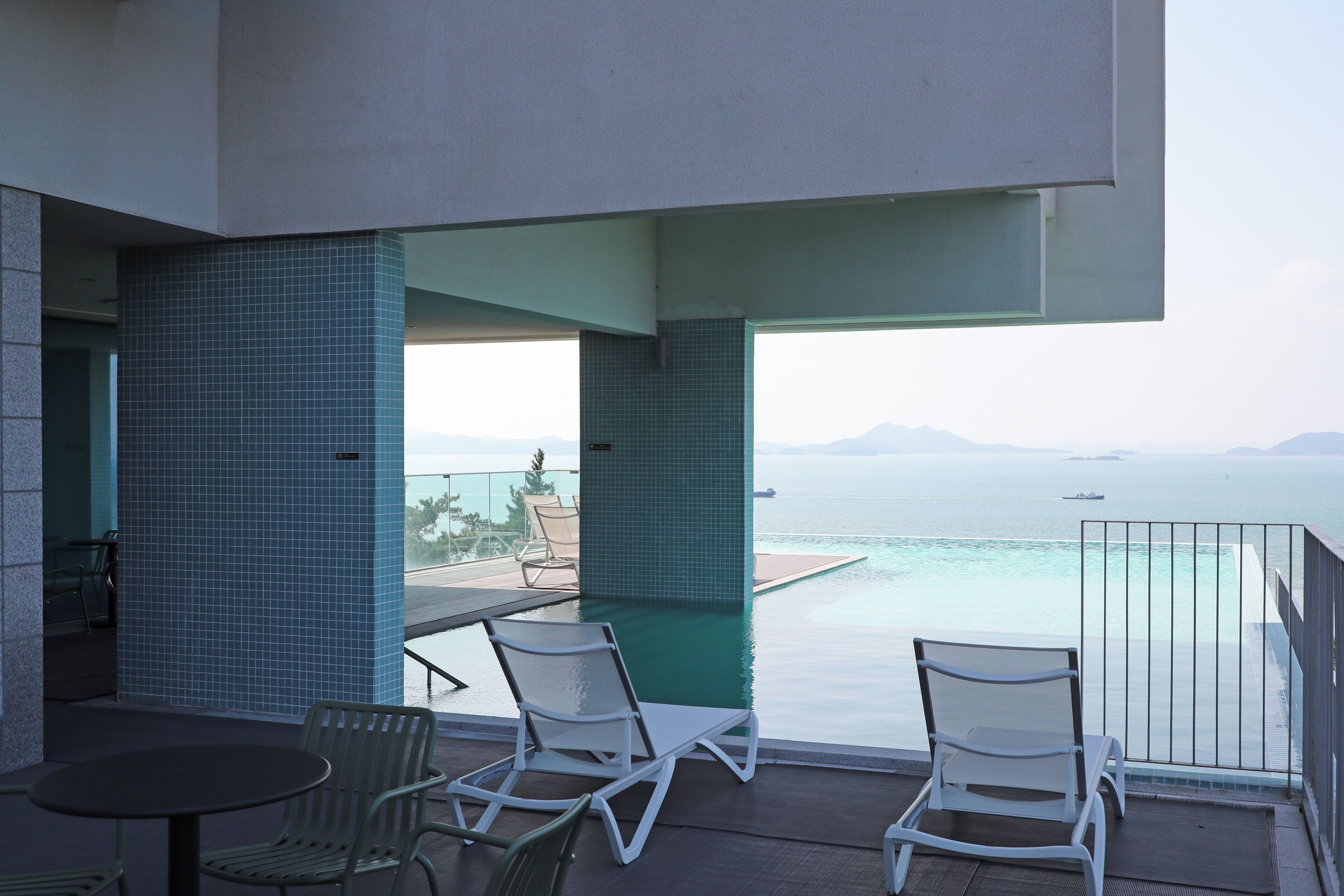En balkon med pool, to liggestole og et bord.