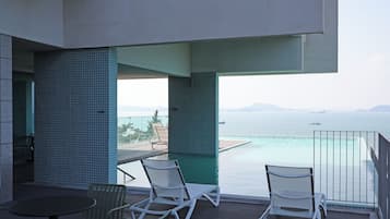 En balkon med pool, to liggestole og et bord.