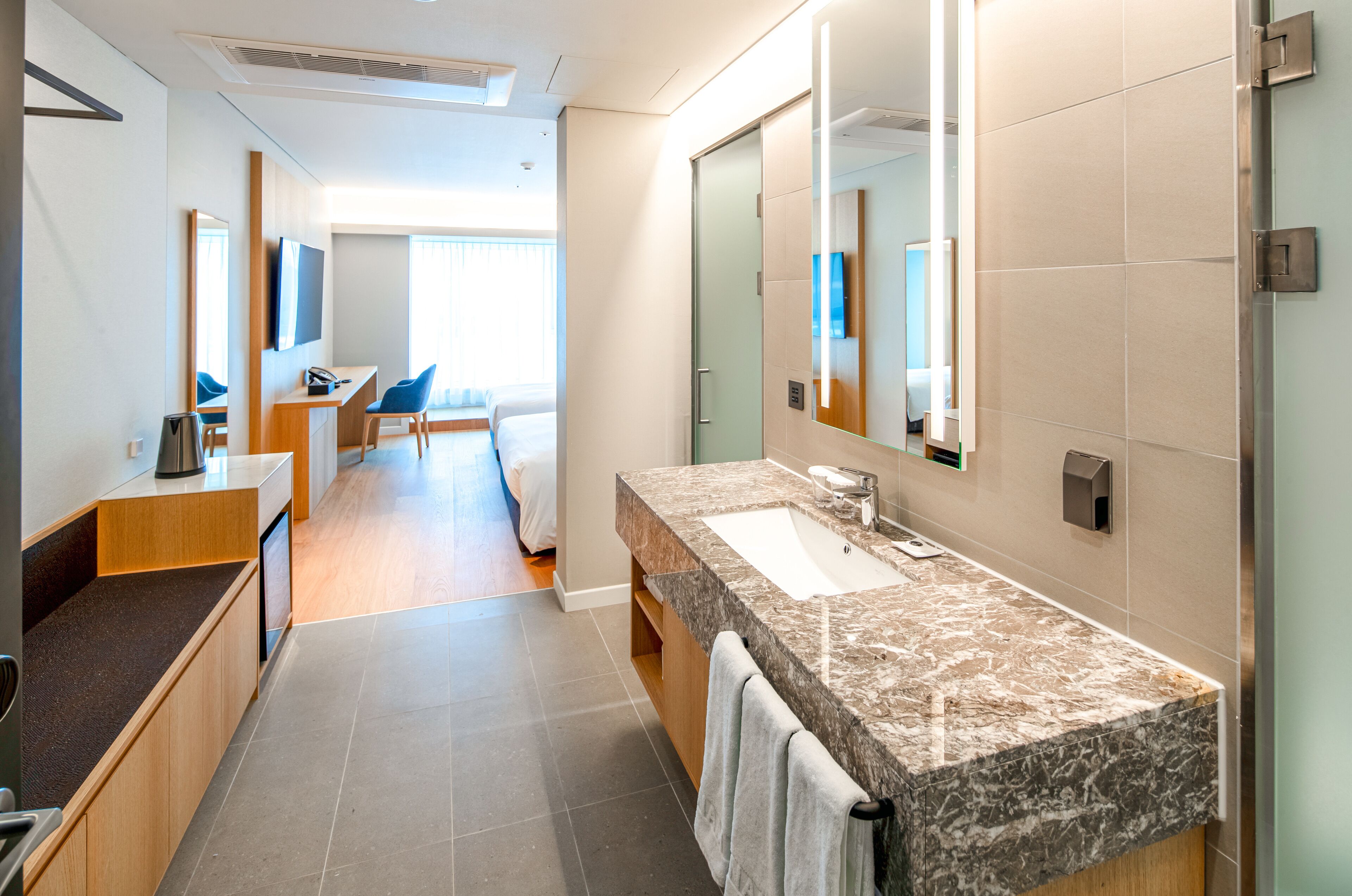 A modern hotel bathroom with a large sink, mirror, and a shower area.
