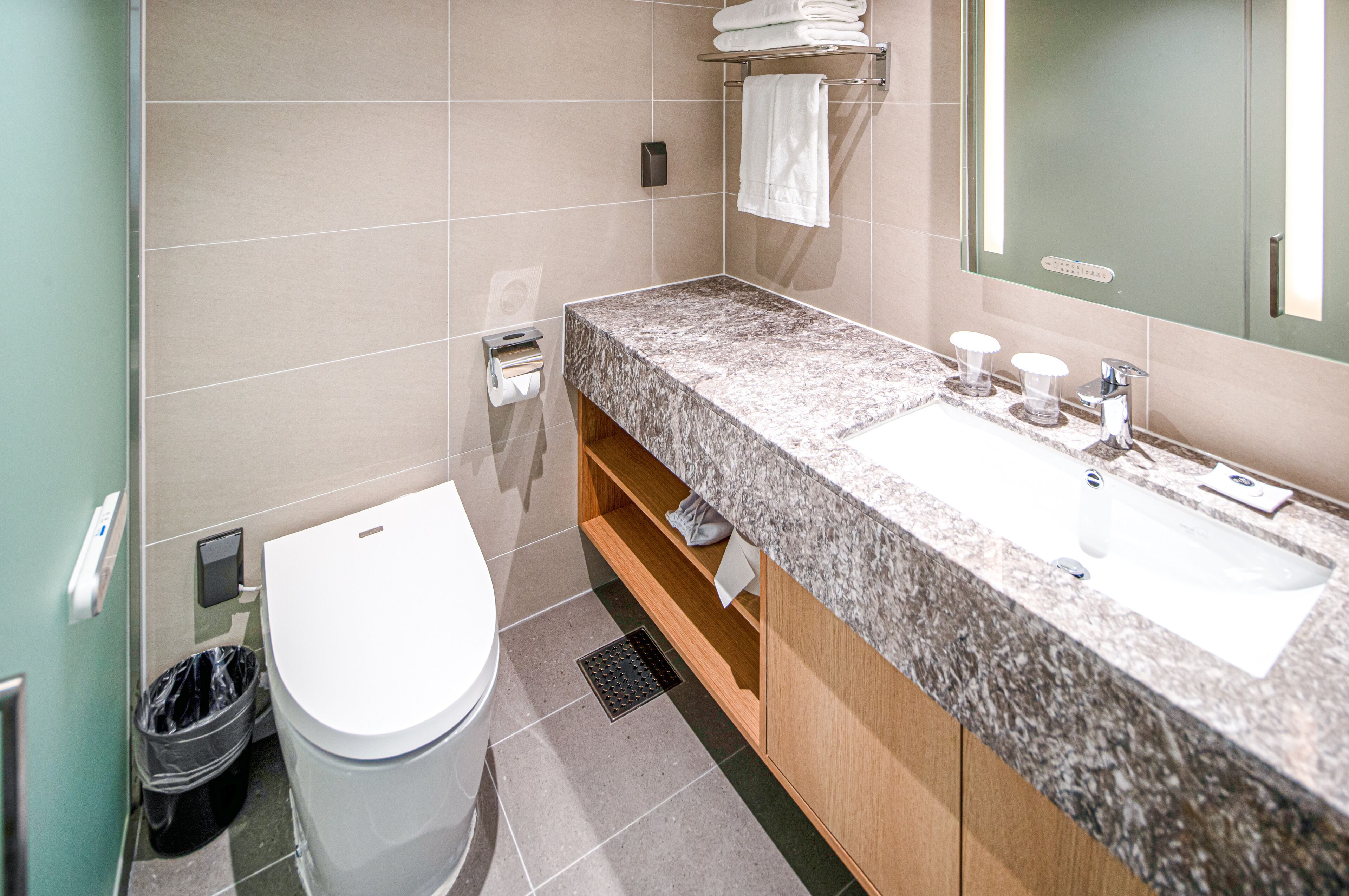Un baño moderno con encimera de mármol, un lavabo blanco y un espejo.