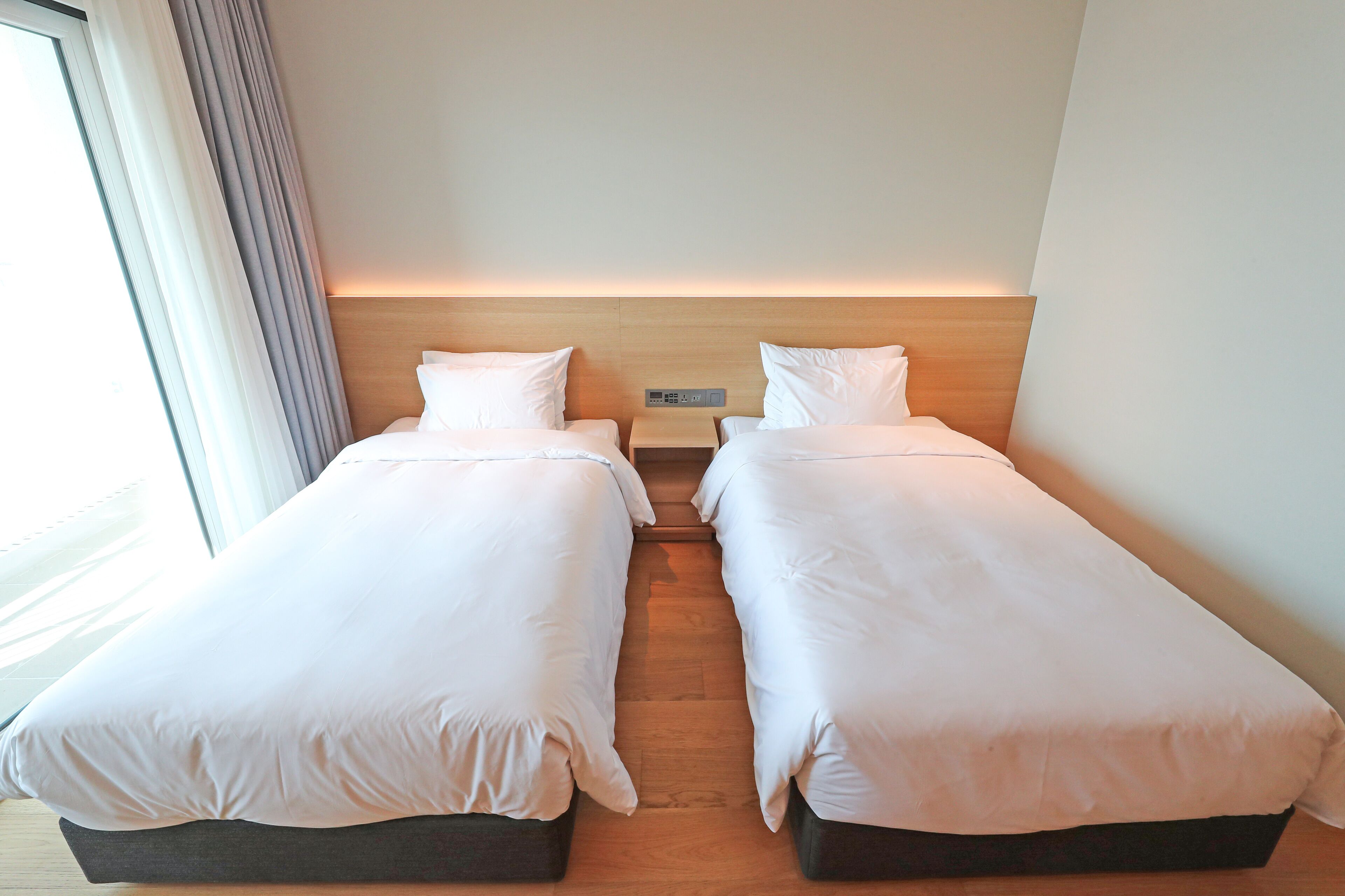 Una habitación de hotel con dos camas individuales, una mesita de noche y un tocador.